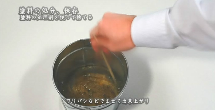 さげ缶に入った塗料と処理剤を割り箸で混ぜる